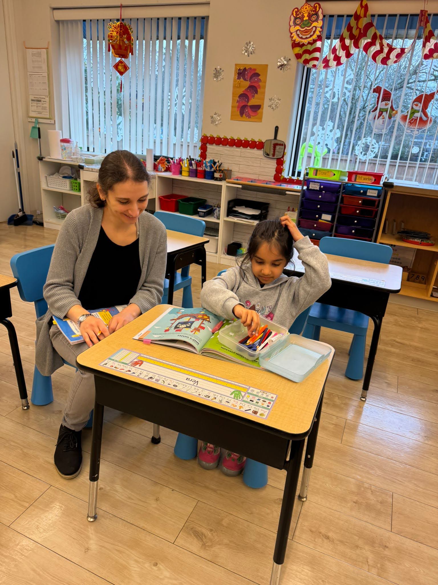 Teacher and student at a desk in a classroom setting