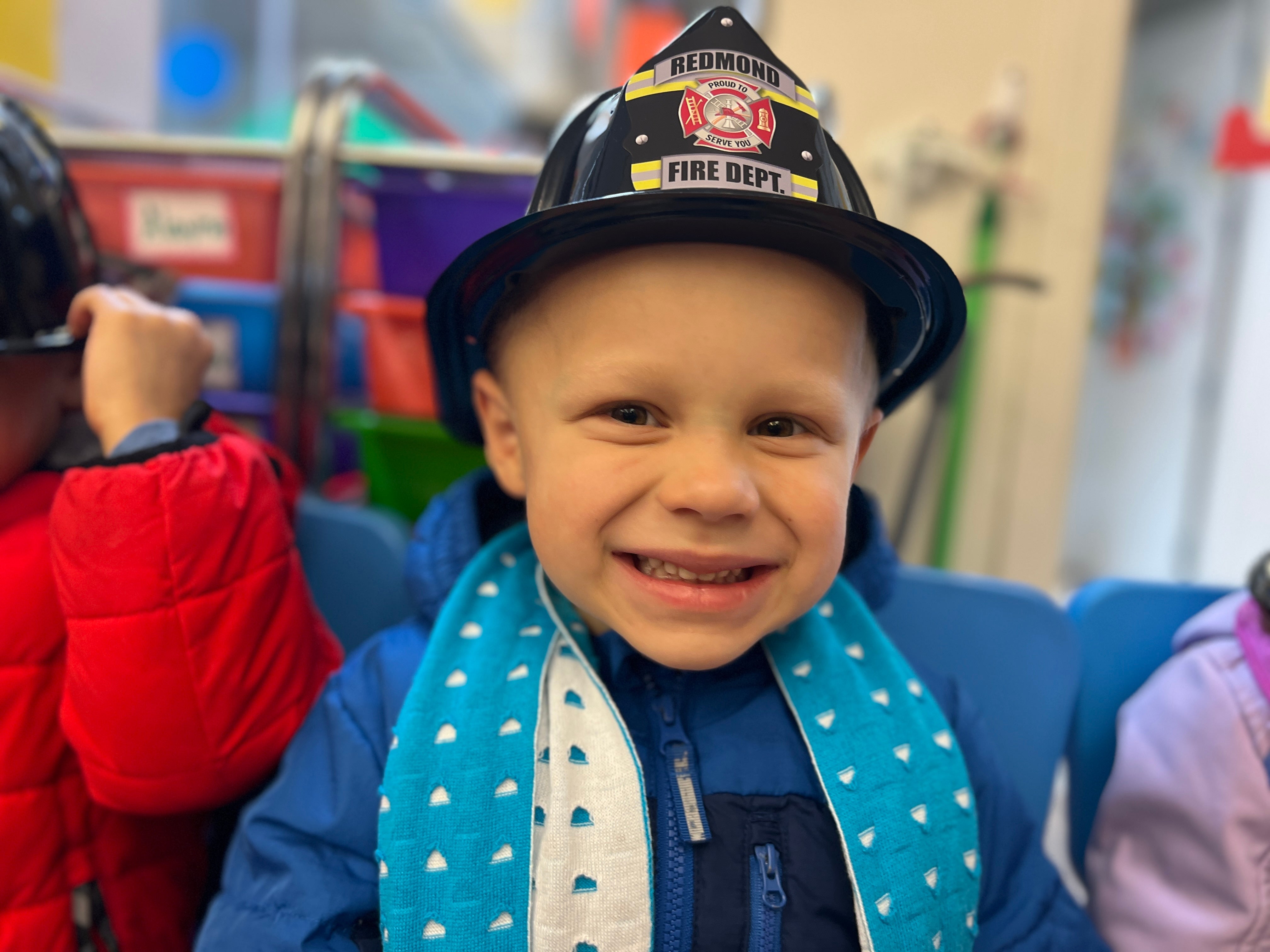 Child wearing a fire department hat in an indoor setting