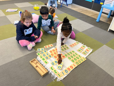 Children playing with educational number mats on a classroom floor.