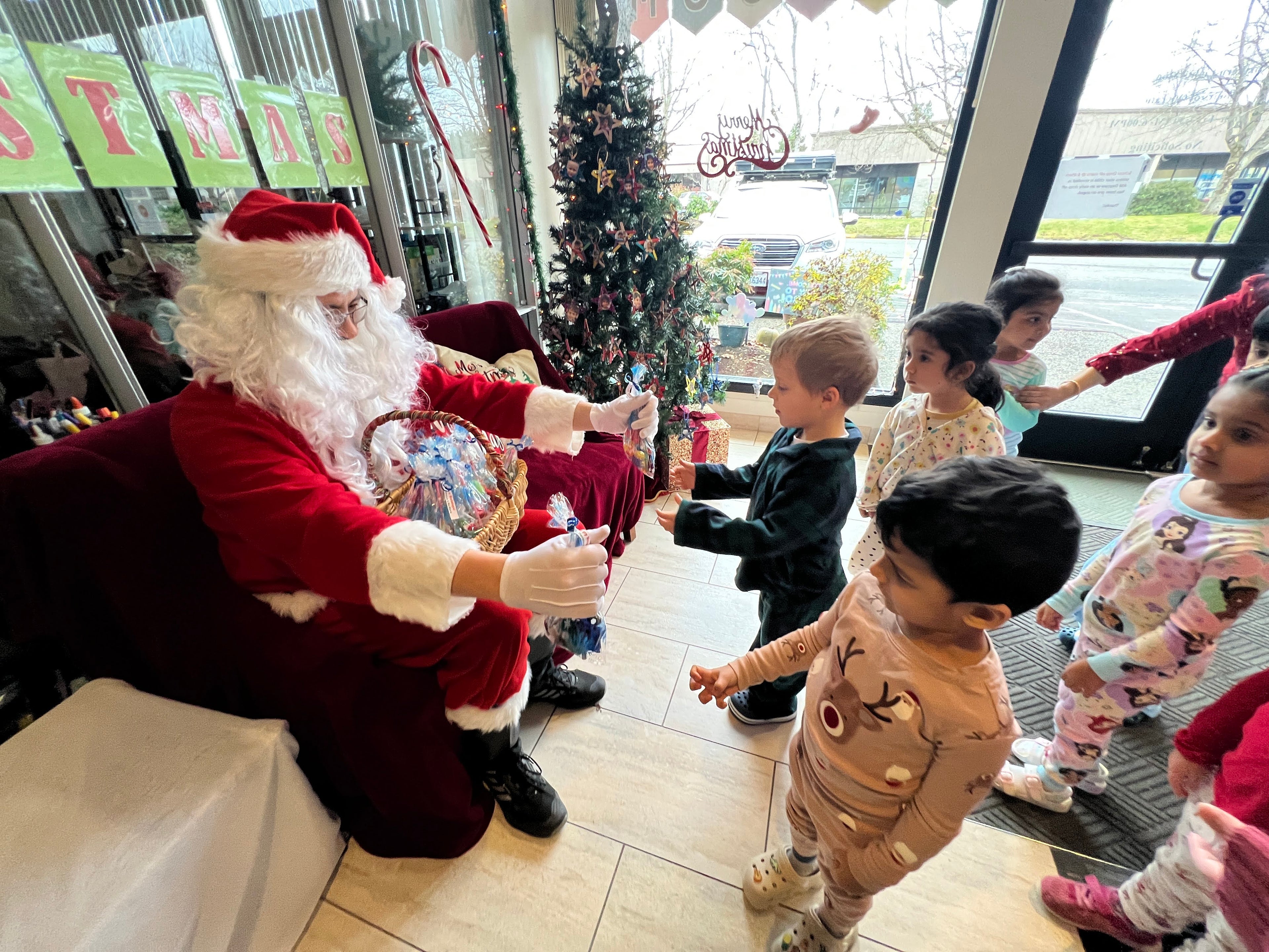 Santa Claus interacting with children in a festive indoor setting.