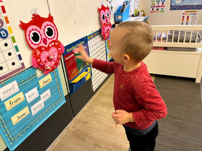Child interacting with educational materials on a wall in a classroom setting