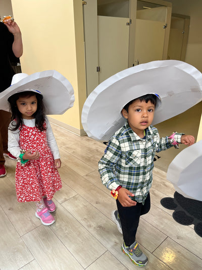 Two children playing with a large white object on a wooden floor.