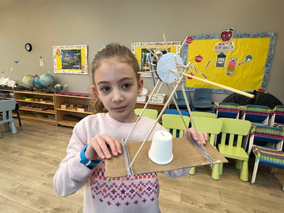 Young girl holding a science project in a classroom setting